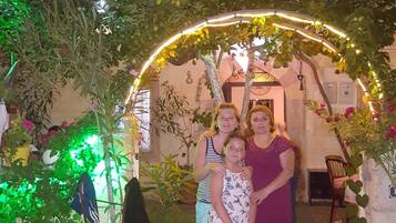 Uma família em pé sob um arco decorativo com o texto "Nil Story House" visível acima.