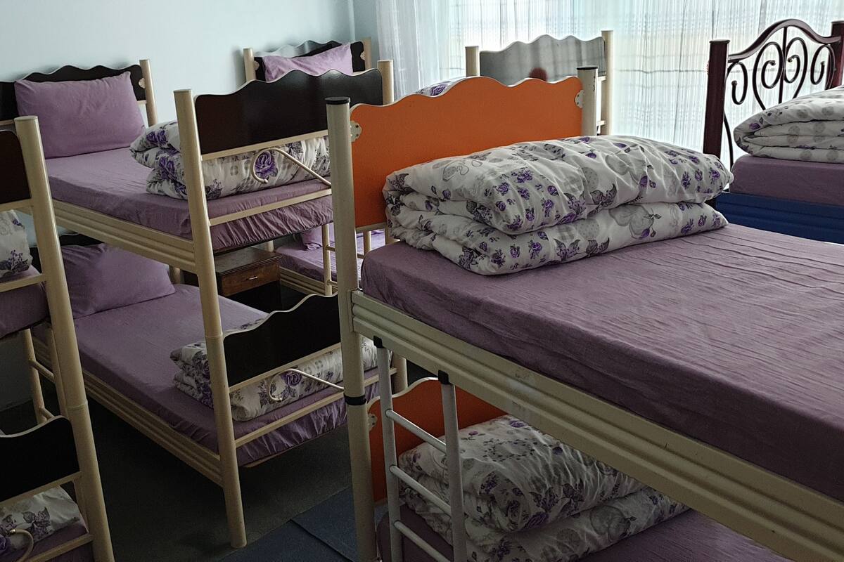 Ein Schlafsaalzimmer mit Etagenbetten, jeweils mit violetten Matratzen und blumigem Bettzeug.