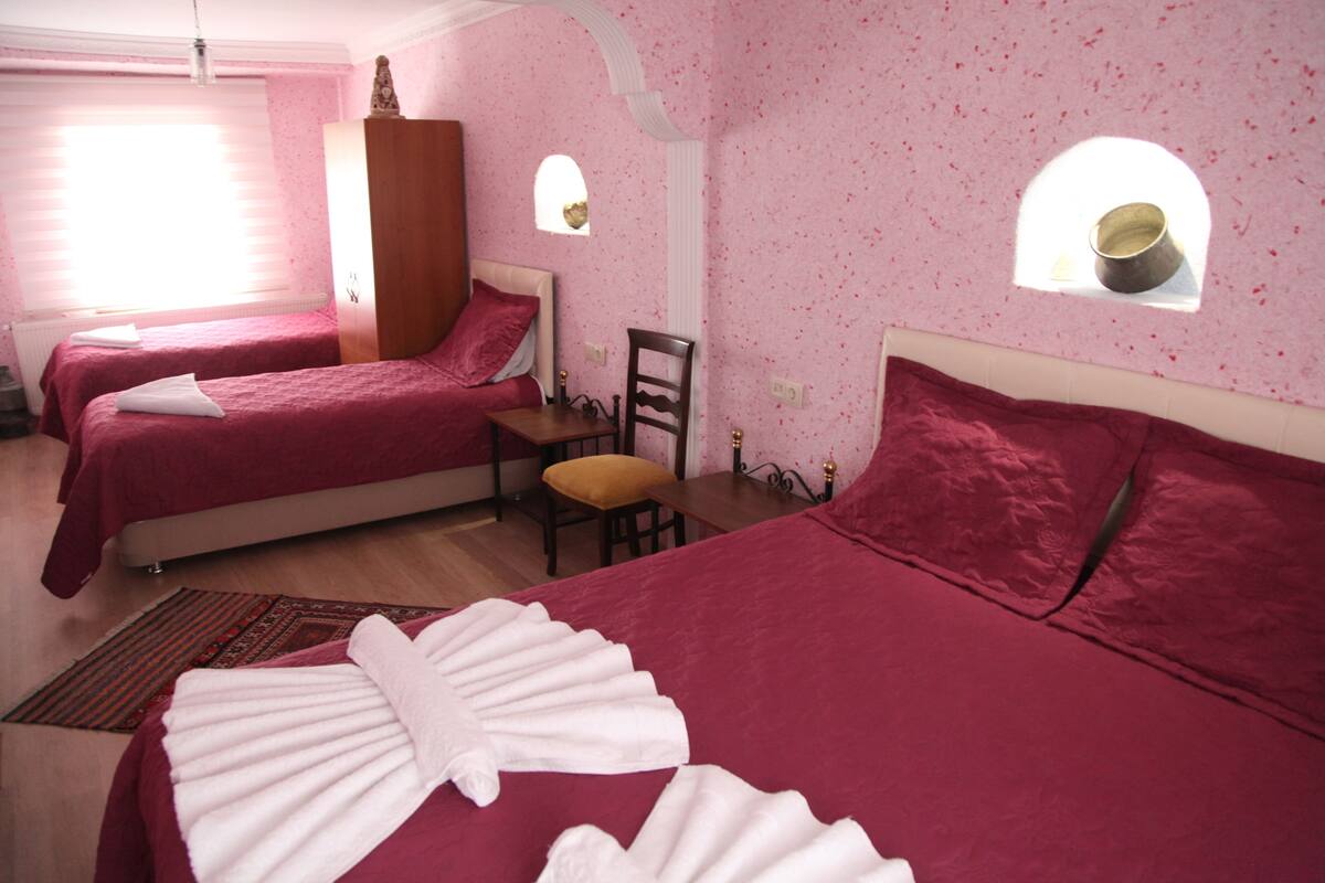 Ein Zimmer mit zwei Betten, einem Holzschrank, einem kleinen Tisch und zwei Stühlen.