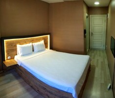 A bedroom with a wooden headboard, a bed with white linens, a nightstand, and a door in the background.