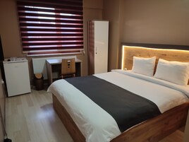 A bedroom with a bed, a desk, and a wardrobe.