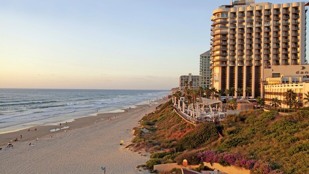A beachfront hotel with multiple balconies, a sandy beach, and a view of the ocean. - Raphael Apartments (Herzliya)