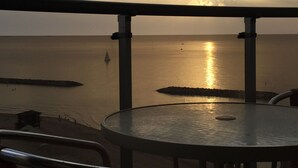 A round table with a metal frame, overlooking a calm sea with a sunset. - Raphael Apartments (Herzliya)