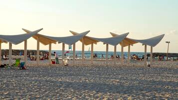 A beach with multiple shaded areas and a sandy beach.