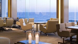 A restaurant with a view of the ocean, featuring tables and chairs arranged for dining. - Raphael Apartments (Herzliya)