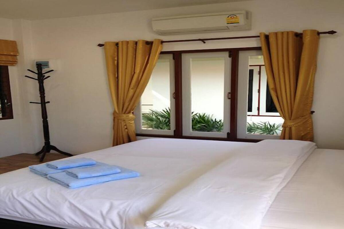 Quarto de hotel com cama, cabideiro e vista para o exterior através de uma porta.