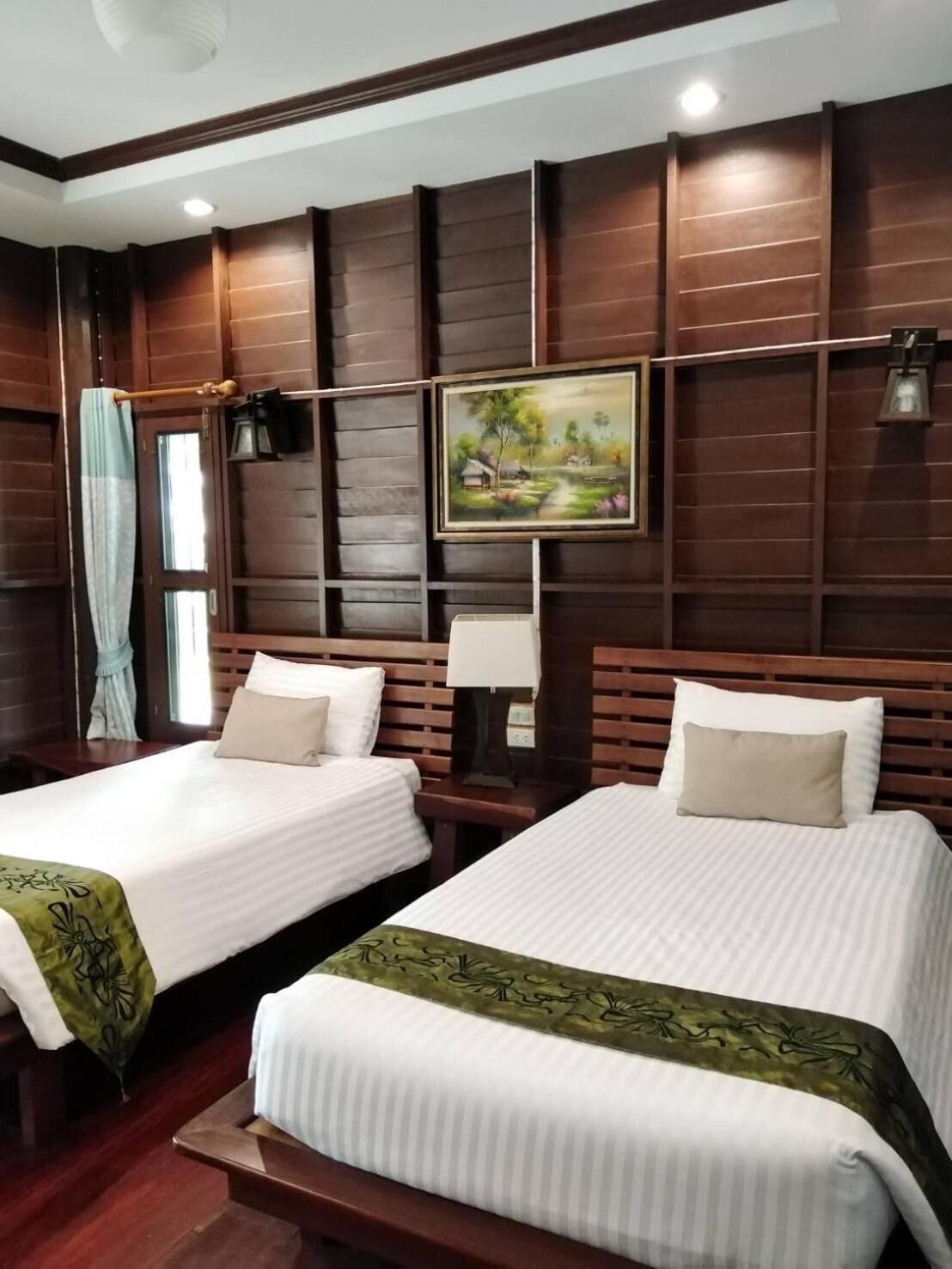 Habitación de hotel con dos camas, un cuadro en la pared y un ventanal con cortinas.