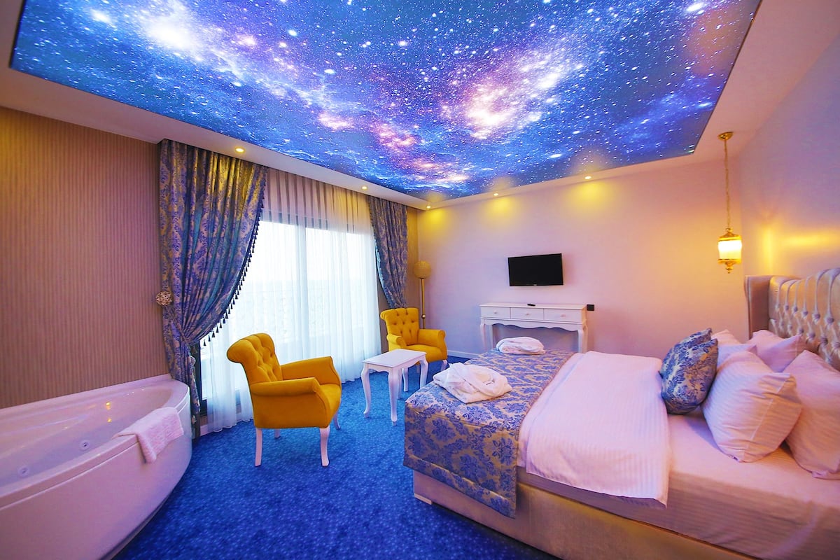 Quarto de hotel com cama, poltrona, escrivaninha e banheira.