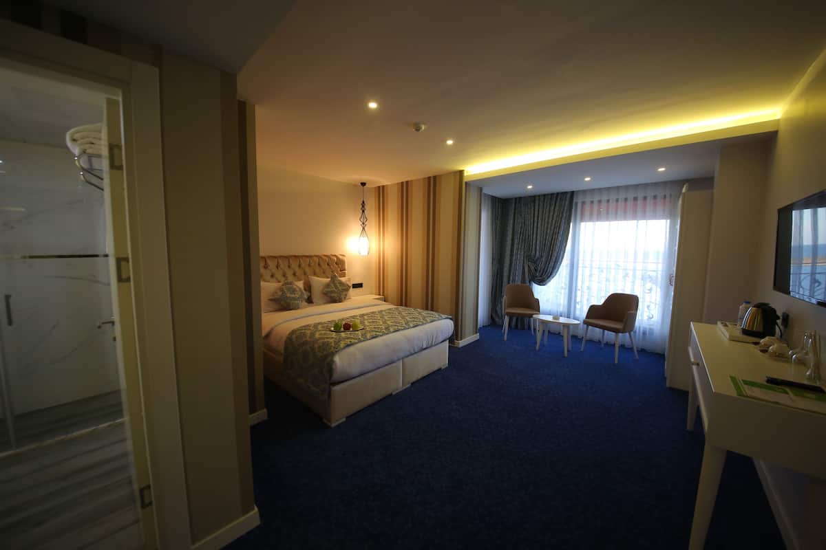 Quarto de hotel com uma cama grande, uma escrivaninha, uma cadeira e uma televisão.