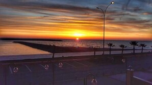 En vacker solnedgång sedd från en strandpromenad med gatlyktor och palmer.
