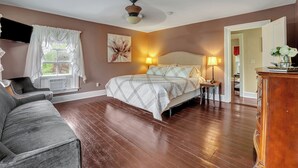 A bedroom with a bed, bedside table, lamp, and a dresser.