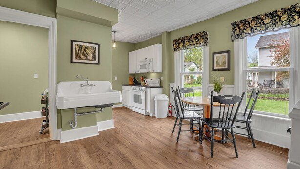 A kitchen with a white sink, white cabinets, and a dining table with black chairs.