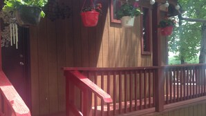 Eine Holterrasse mit Stufen, die zu einer Tür führen, verziert mit hängenden Pflanzen und Lichterketten.