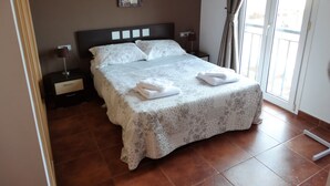 A neatly made bed with a floral bedspread, a bedside table with a lamp, and a painting on the wall.