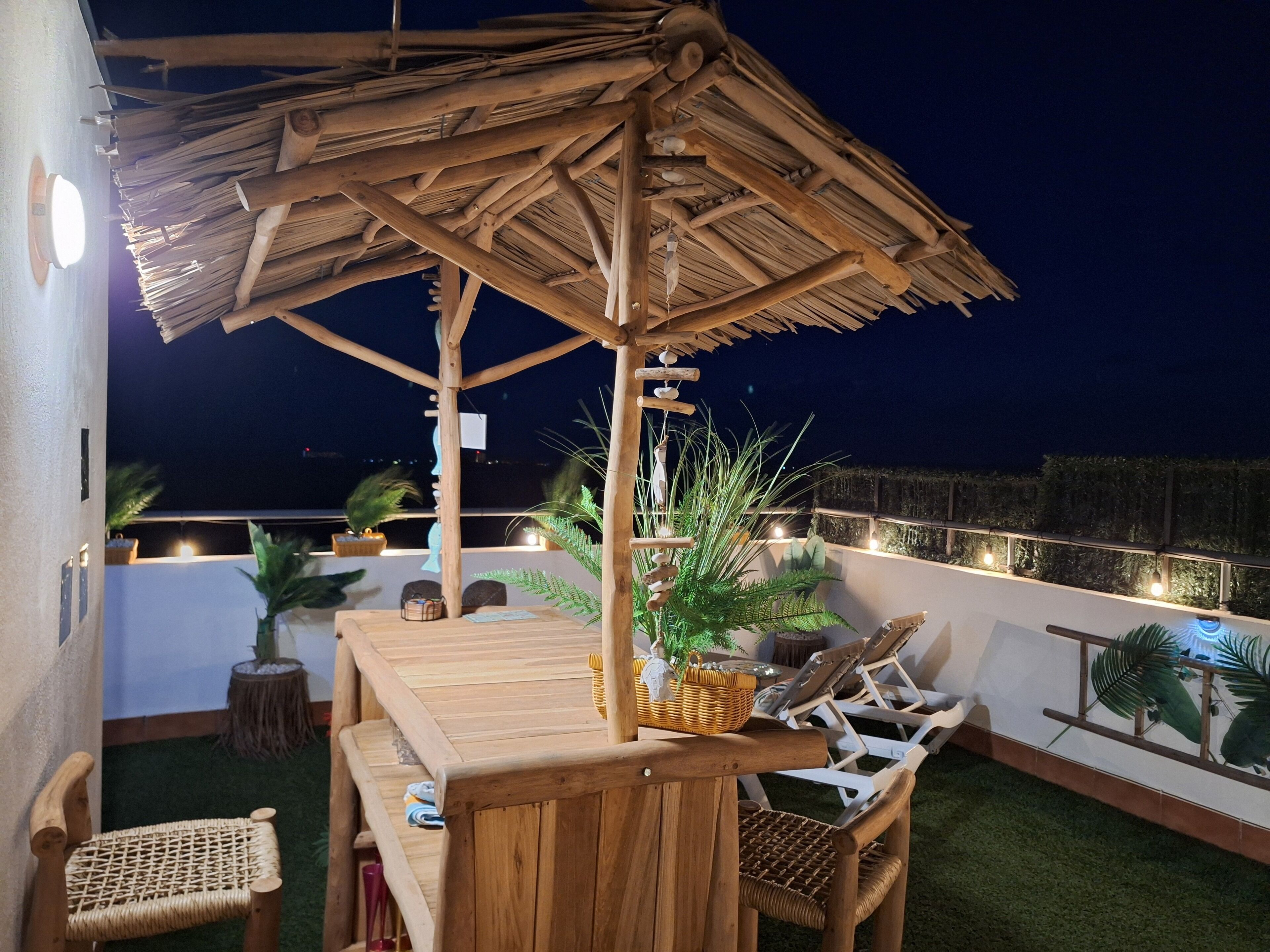 Une terrasse extérieure dotée d’une pergola en bois, de chaises longues et d’une table à manger.