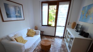 Une pièce avec un canapé blanc, un pouf en osier, une petite table, un meuble et une carte du monde accrochée au mur.