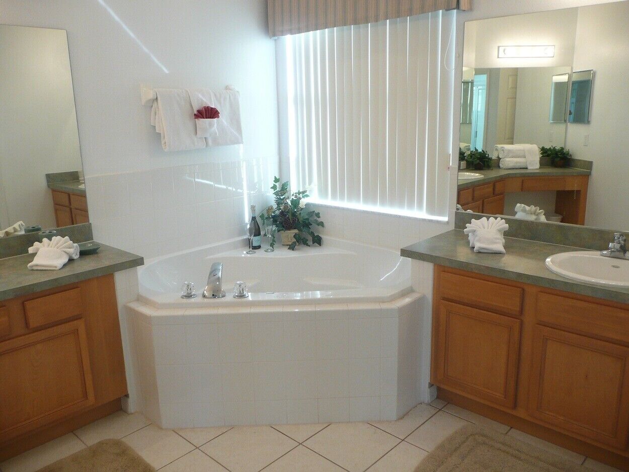 Un baño moderno con una bañera independiente, dos lavamanos, armarios de madera y un espejo grande.