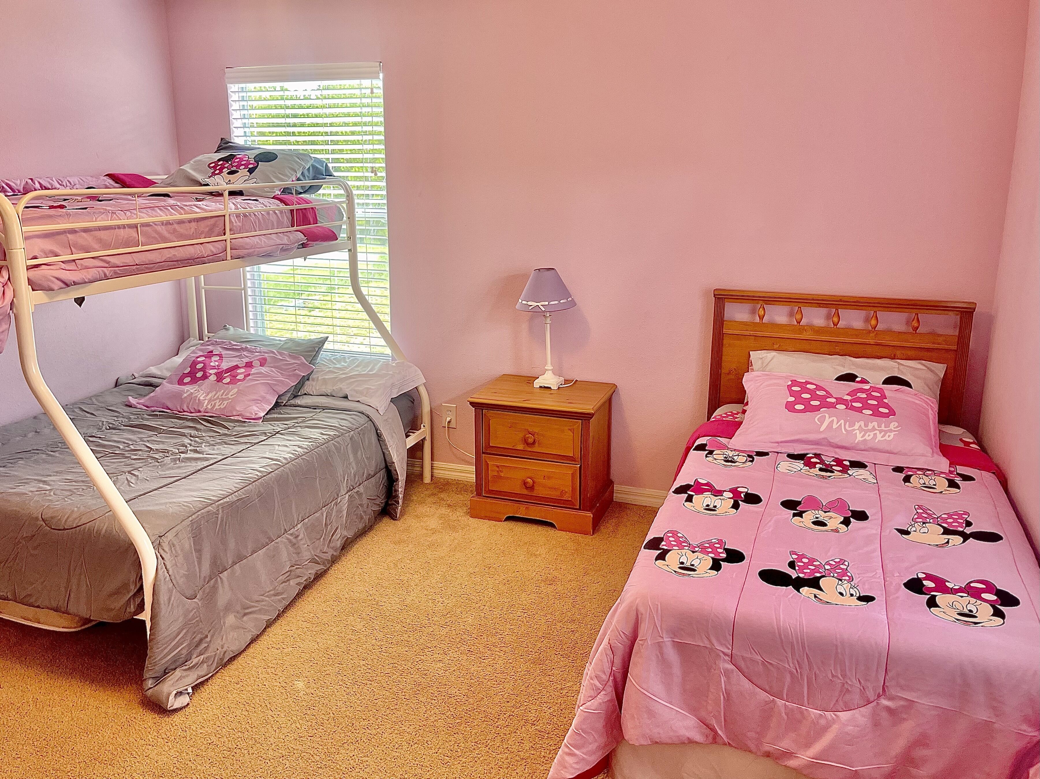 A bedroom with bunk beds, a nightstand, and a window with blinds.