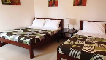 Una habitación de hotel con dos camas, cada una con una colcha estampada, una mesita de noche con lámpara y dos cuadros en la pared.