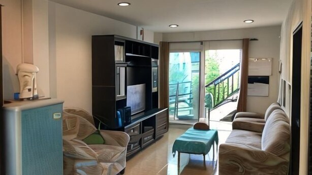 A living room with a TV, sofa, and a small table. - Kitti Rose Home (Chiang Mai)