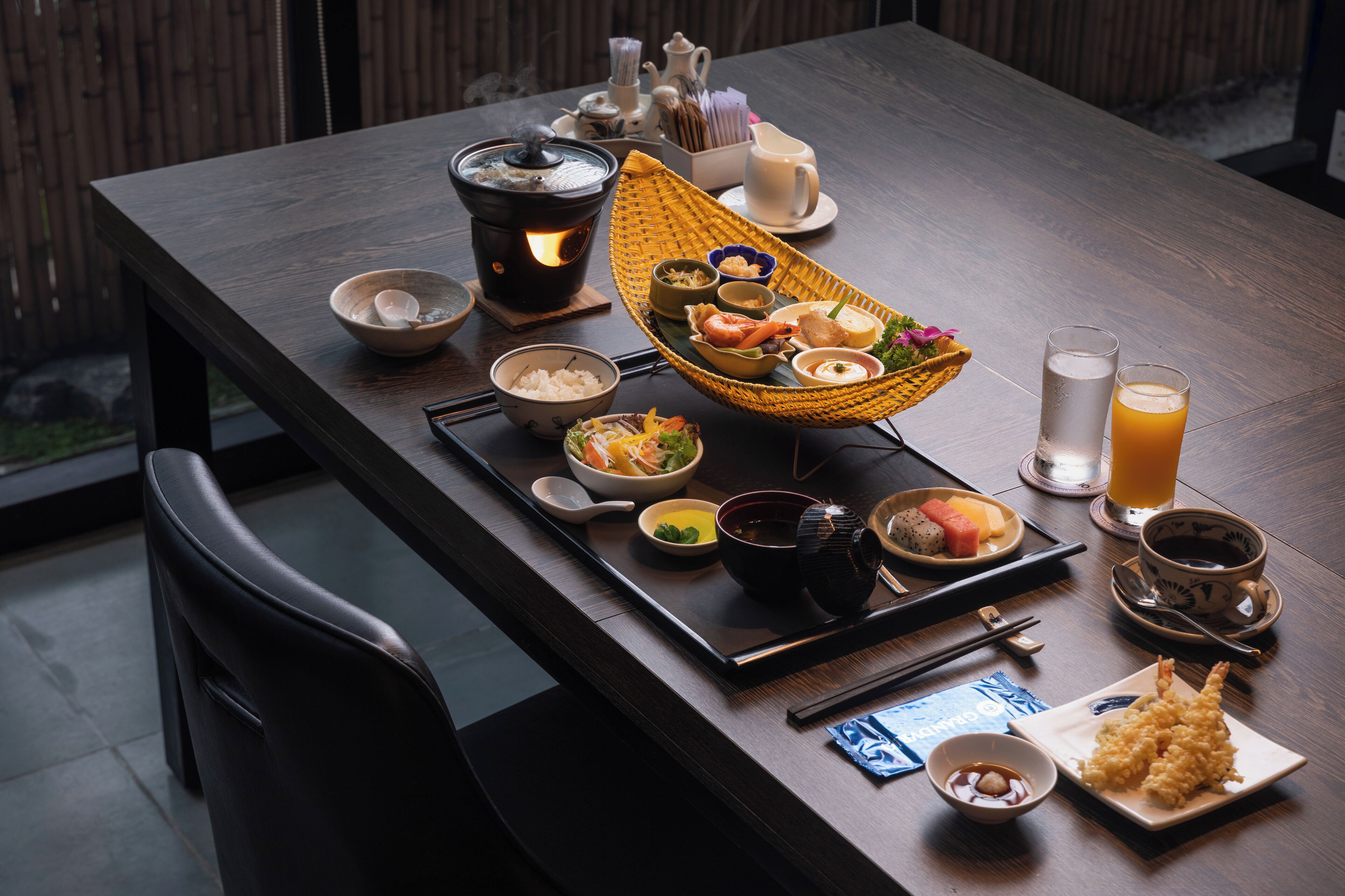 A dining table set with various dishes, including sushi, a hot pot, and drinks.