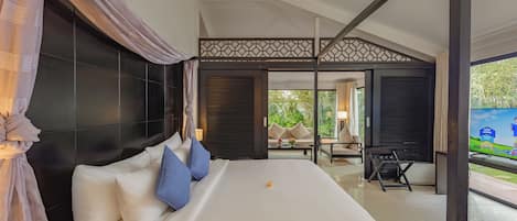 A hotel room with a large bed, a view of the outdoors, and a balcony with seating.