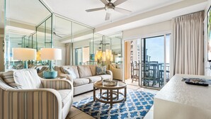 Una habitación de hotel moderna con sofá, mesa de centro, televisor y balcón con vistas.