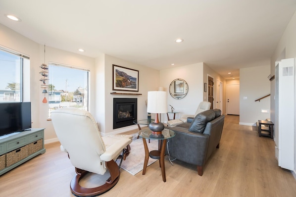 A modern living room with a fireplace, a television, a sofa, and a glass coffee table.