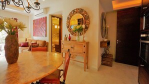 Een eetgedeelte met een houten tafel en stoelen, een vaas met bloemen, een spiegel en een kast met decoratieve voorwerpen.