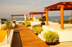 Une terrasse sur le toit, dotée d’un sol en bois, de plantes en pot et d’une structure en forme de pergola.