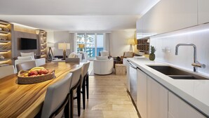Una habitación de hotel moderna con comedor, cocina y un balcón con vistas.