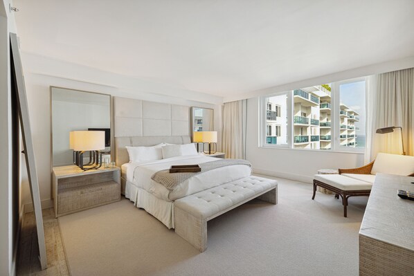 Una habitación de hotel moderna con una cama grande, zona de estar, escritorio y vistas a la ciudad.