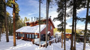 A cabin with a snow-covered roof, surrounded by tall pine trees. - Secluded Getaway: Private Hot Tub & Forest Views (Breckenridge)