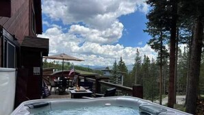 A hot tub with a view of a deck area, outdoor furniture, and a forested landscape. - Secluded Getaway: Private Hot Tub & Forest Views (Breckenridge)