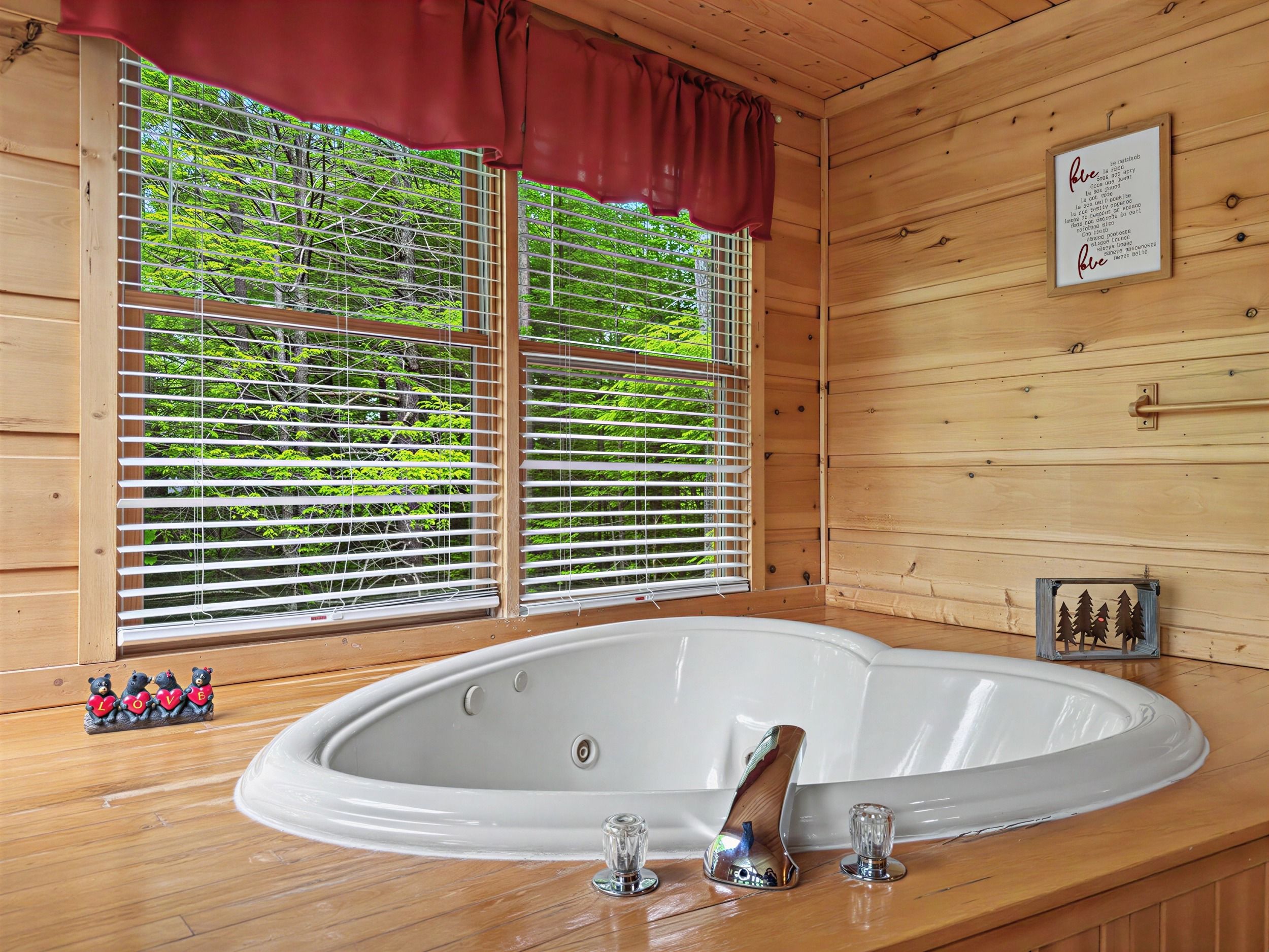 Interieur van een houten hutje met een groot, ovaal bad, een raam met zonwering en een ingelijste citaat aan de wand.