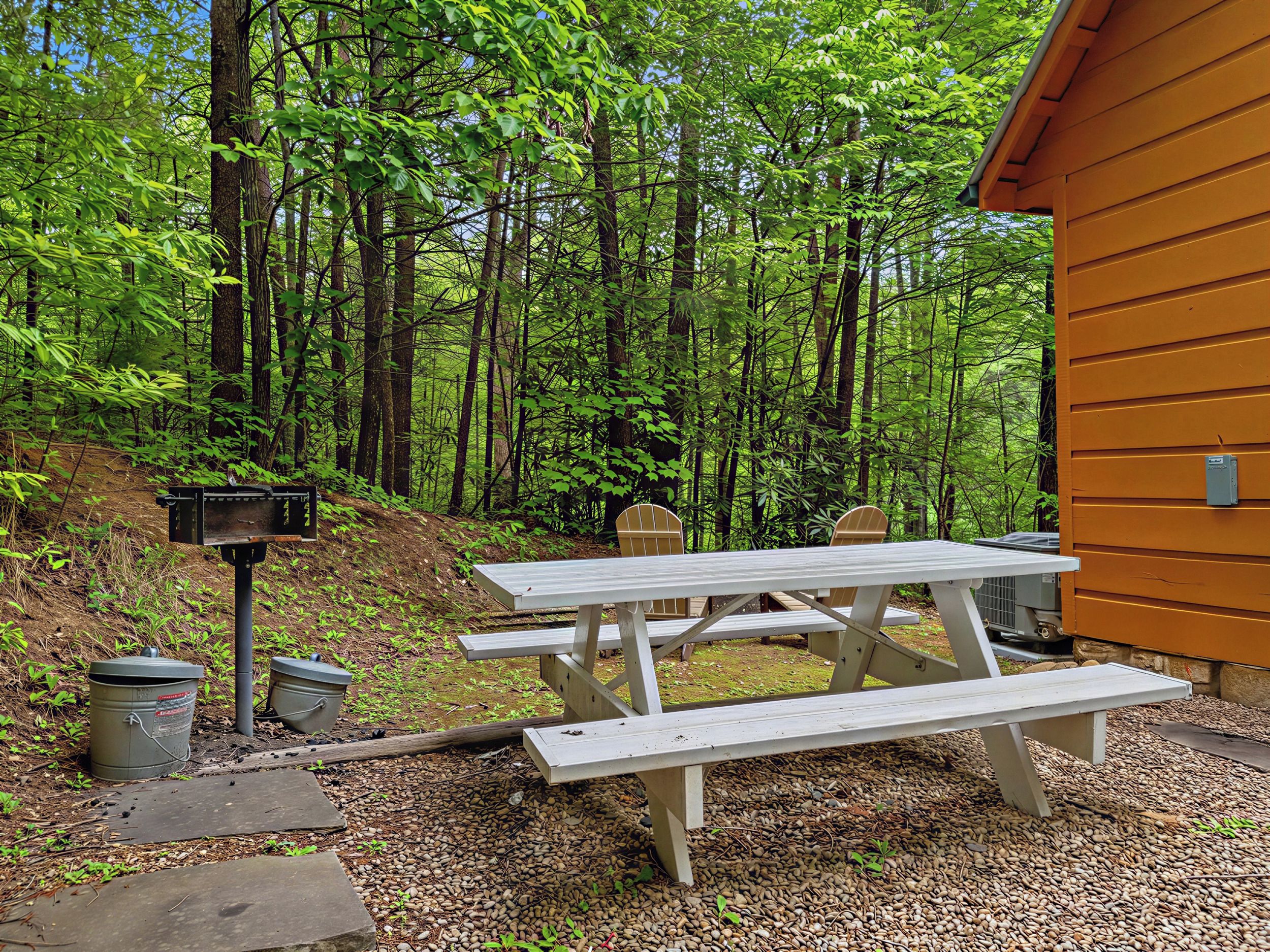 Ein Picknicktisch in einer bewaldeten Gegend, im Hintergrund eine Holzhütte.