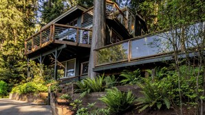 A multi-level wooden structure with outdoor balconies, surrounded by dense greenery. - Sunset View over Lake Whatcom with Hot Tub! (Bellingham)