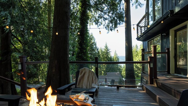 A deck with a fire feature, outdoor seating, and a view of the forest. - Sunset View over Lake Whatcom with Hot Tub! (Bellingham)