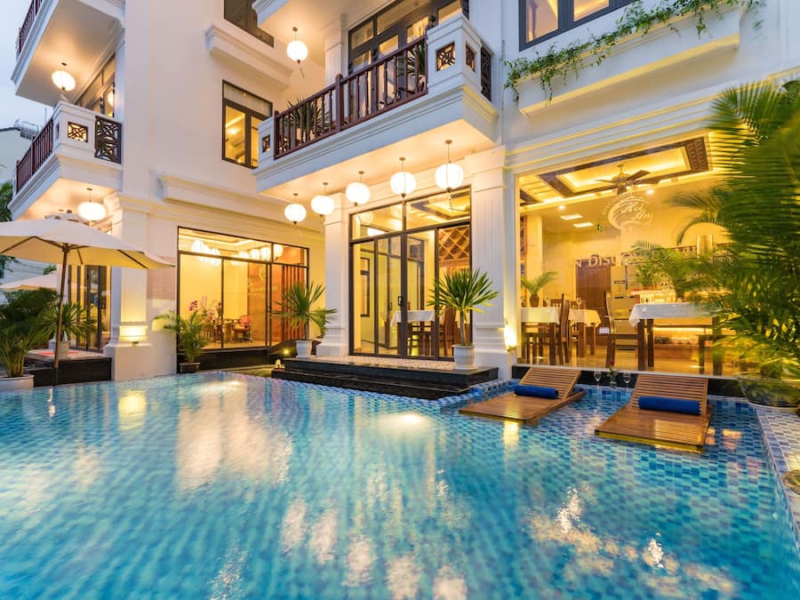 Un hotel con piscina, zona de estar al aire libre y una entrada bien iluminada.