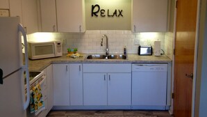 Une cuisine de taille réduite avec des meubles blancs, un four à micro-ondes, un grille-pain et un évier.