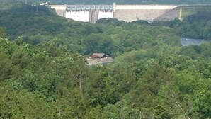 Un grand barrage surmonté d’un pont, entouré d’une forêt dense.
