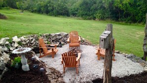 Une terrasse de jardin avec des fauteuils Adirondack, une mangeoire à oiseaux et un mur en pierre.