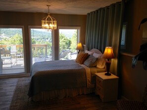 Un dormitorio con una cama grande, dos lámparas de noche, una mesita de noche y vistas a un balcón con mobiliario exterior.