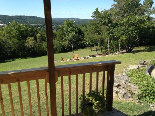 A wooden deck with a view of a grassy area, trees, and distant hills. - IL Capri - Beachy, Breezy European Flat with a Spectacular View! (Hollister)
