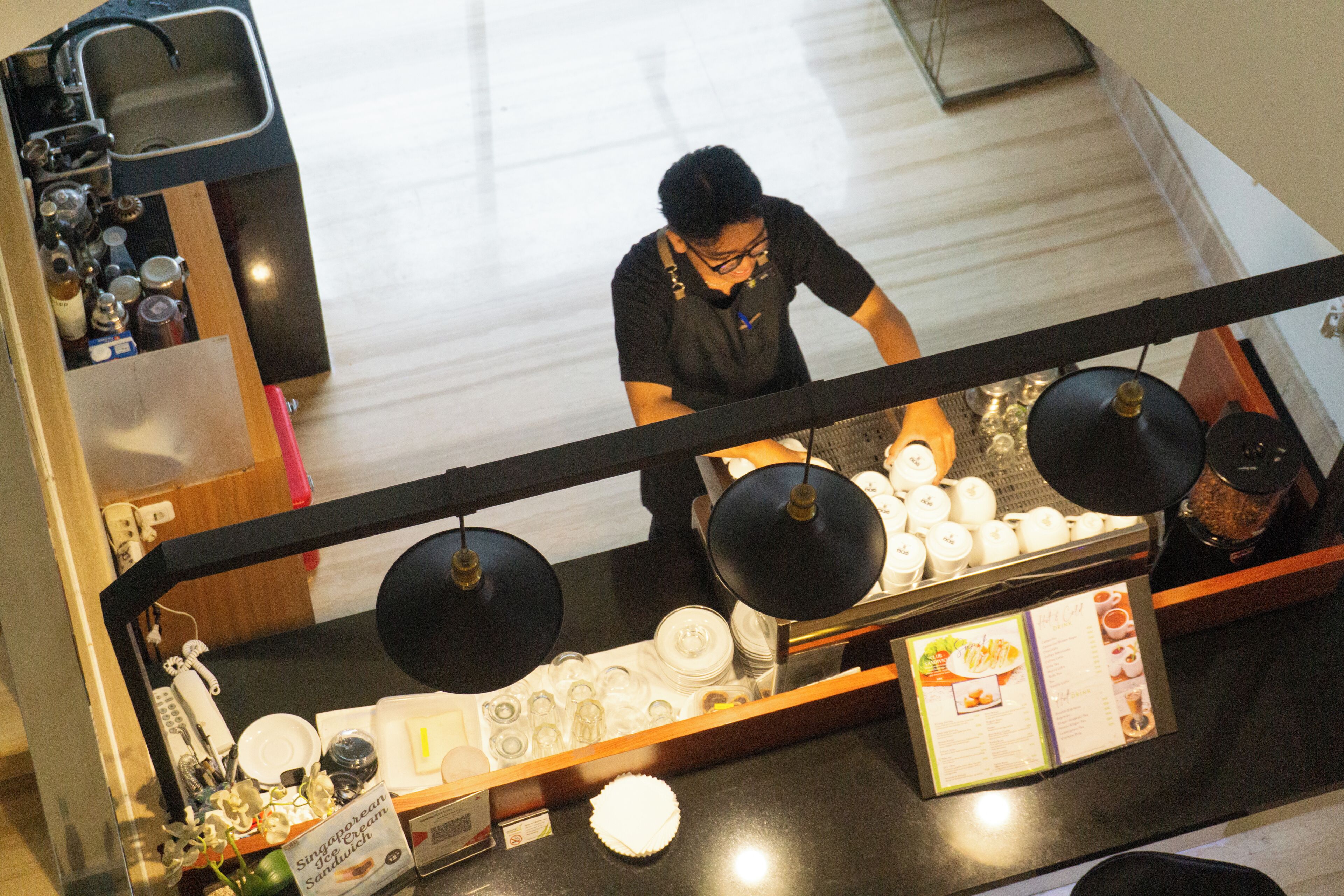 Una cocina con una persona preparando comida, una encimera con varios platos y un cartel de menú.