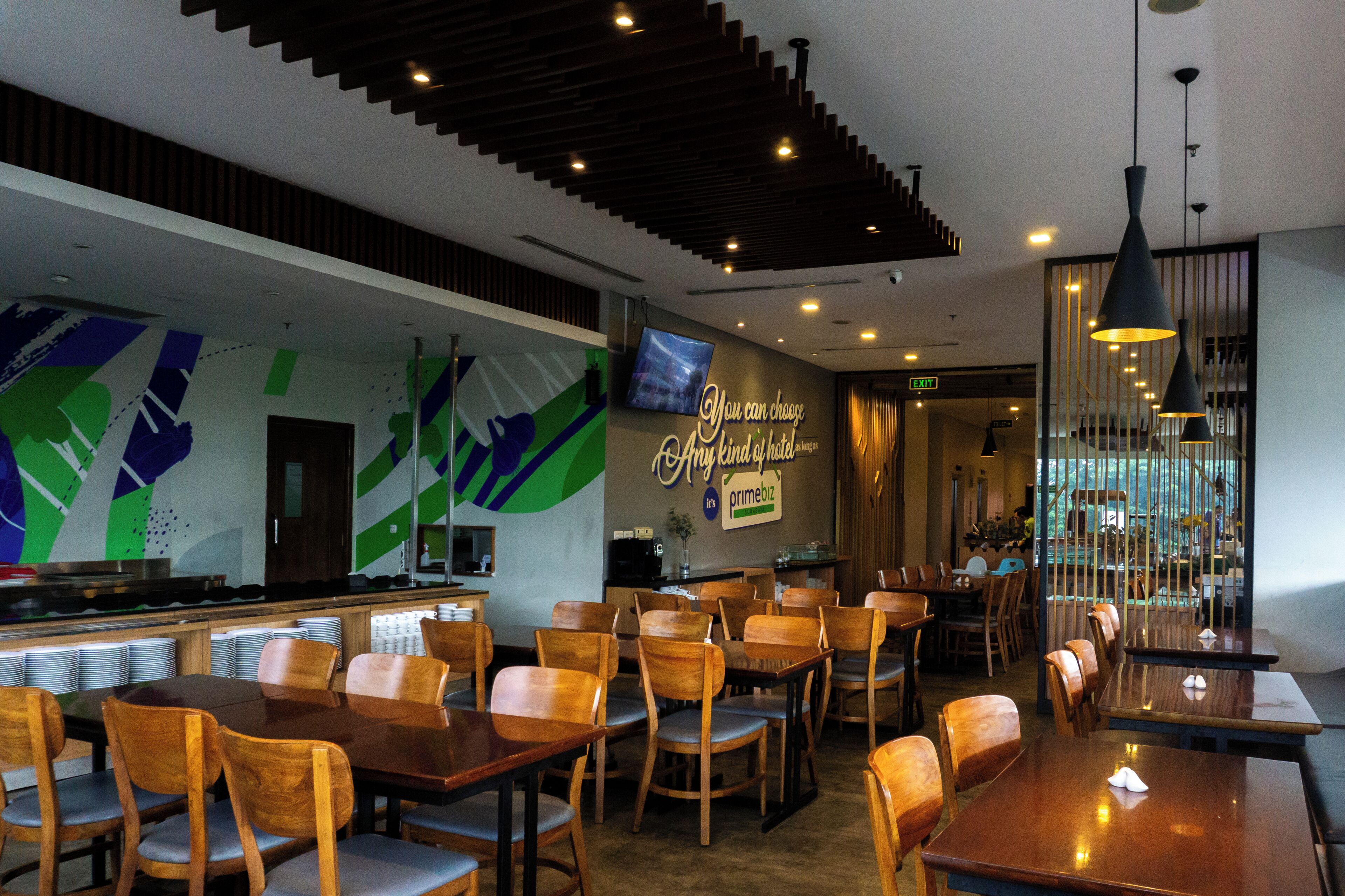 A restaurant with wooden tables and chairs, a bar area, and a wall with a motivational quote.
