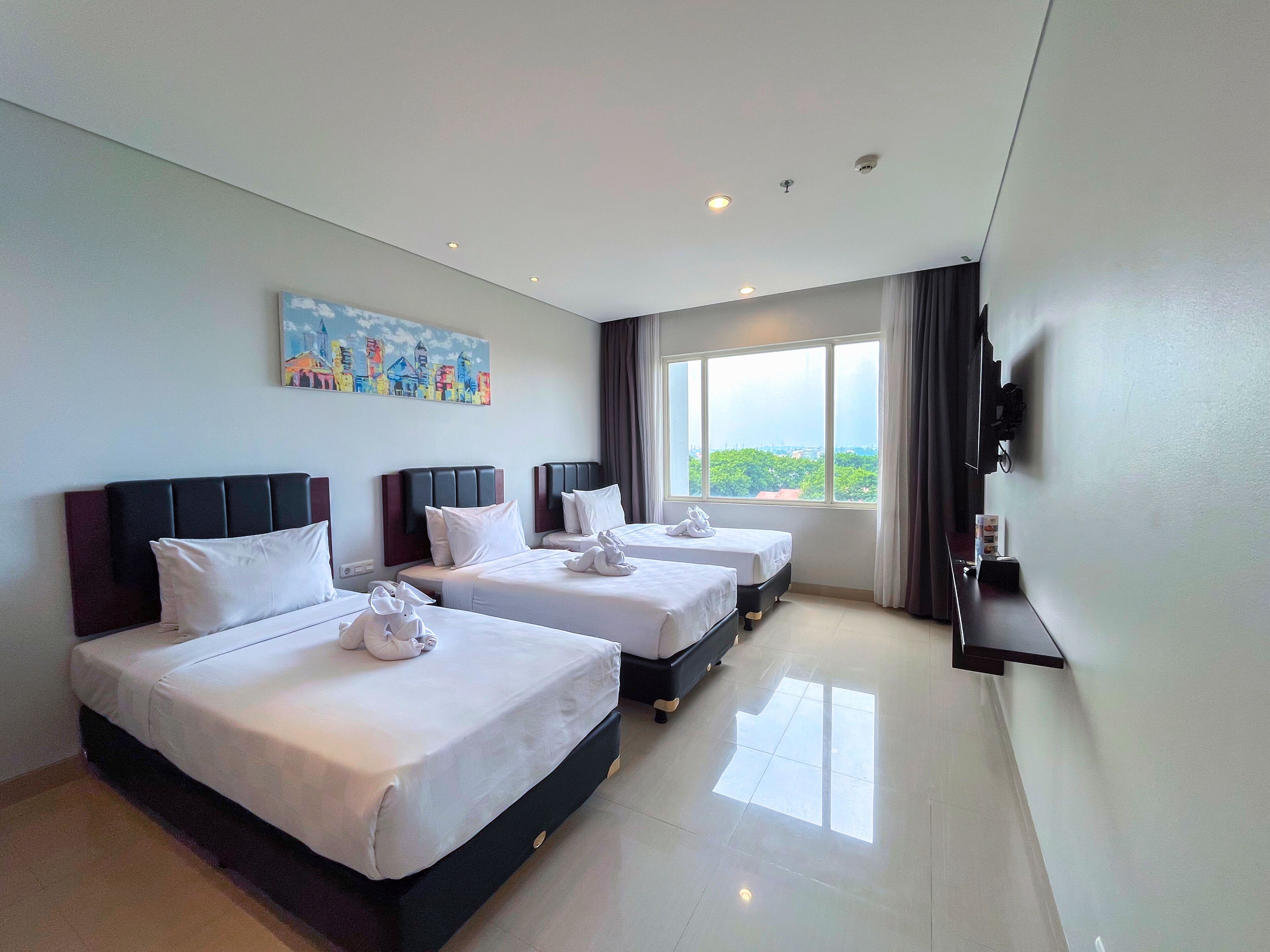 Habitación de hotel con dos camas, un cuadro, un televisor y una ventana con vistas.