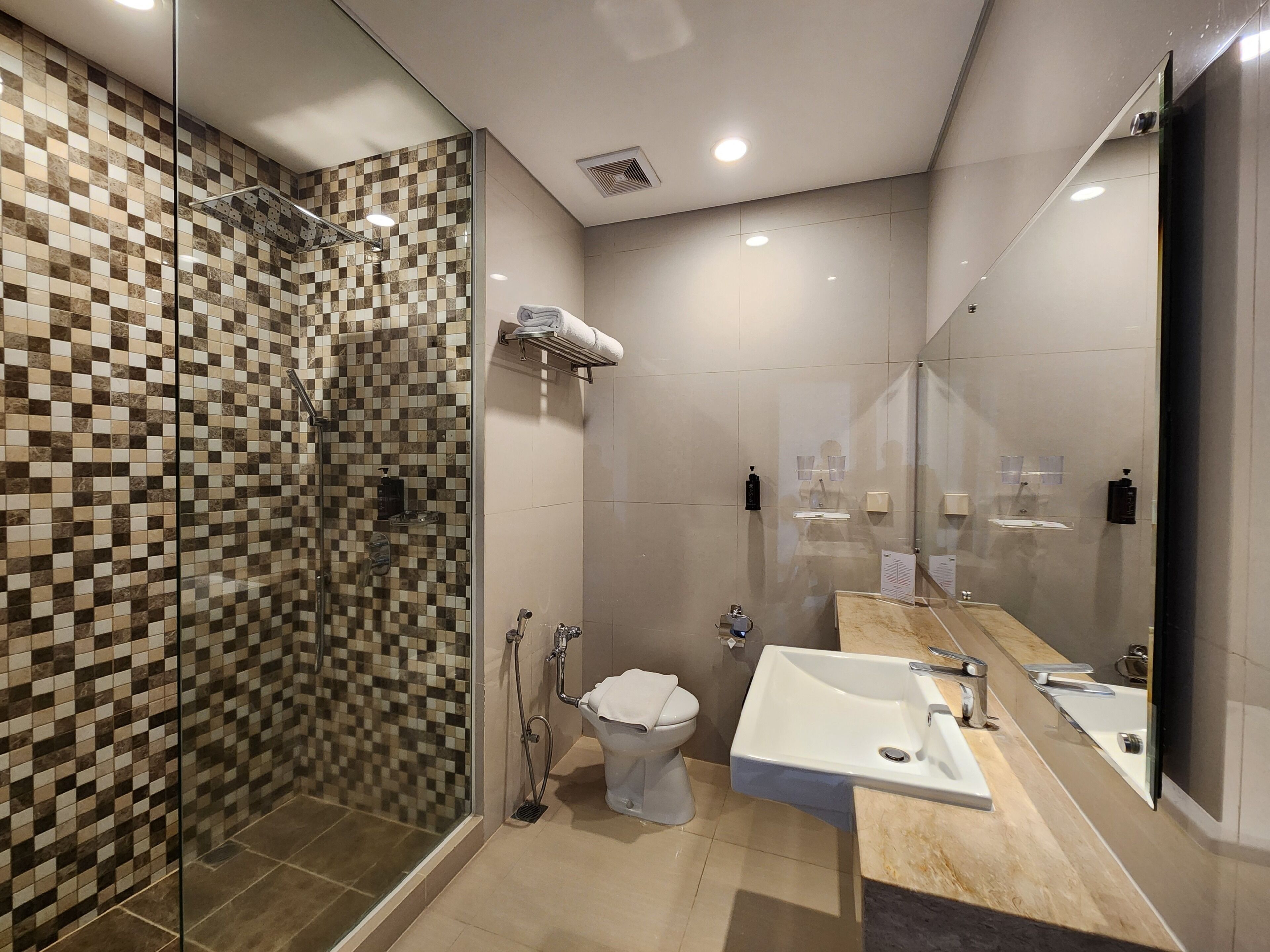 Un baño moderno con cabina de ducha de vidrio, inodoro y lavabo con un espejo grande.