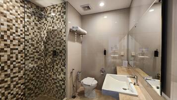 Un baño moderno con cabina de ducha de vidrio, inodoro y lavabo con un espejo grande.