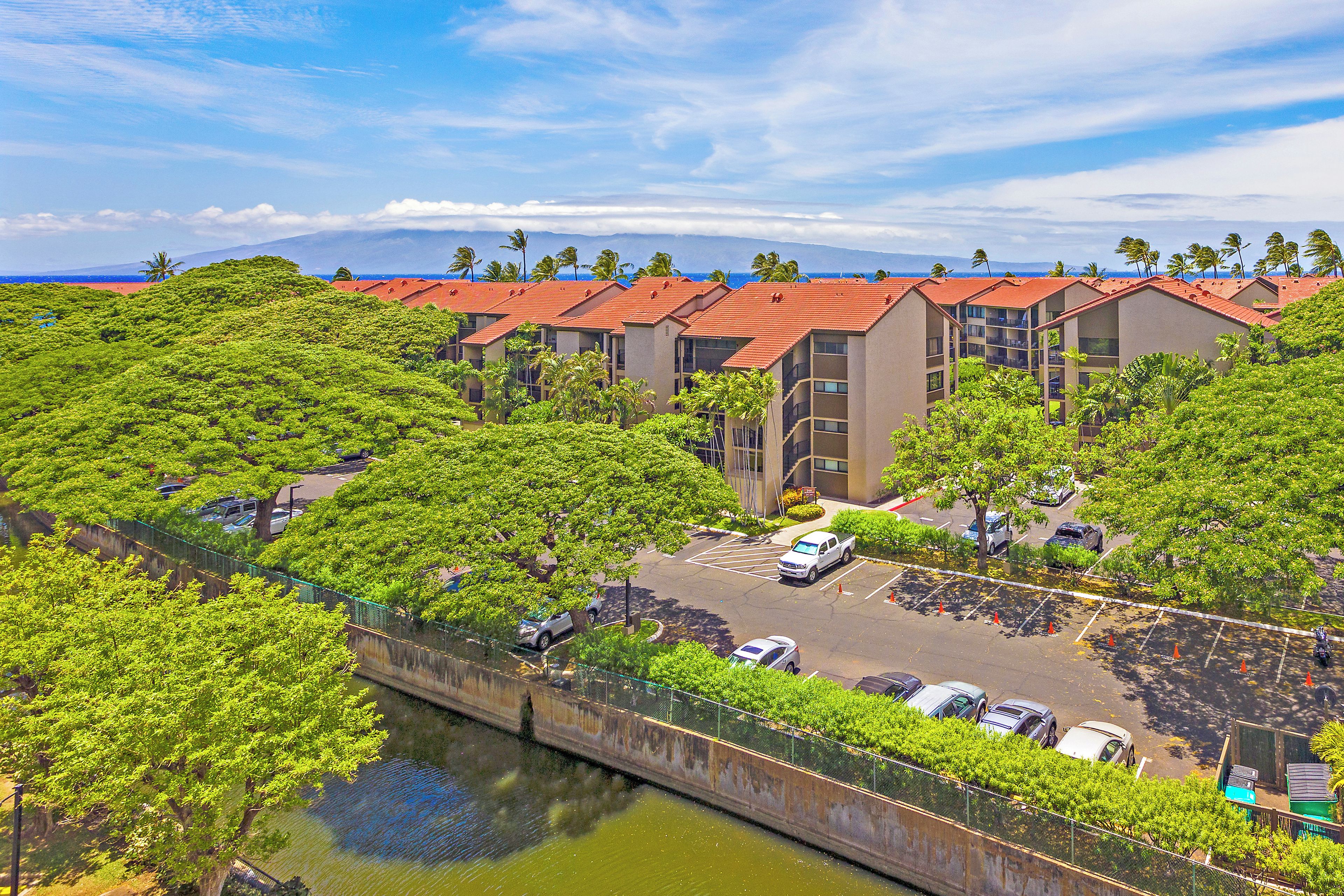 A hotel with multiple buildings, a parking lot, and a river.